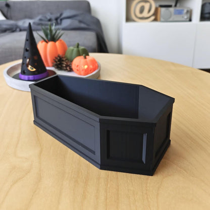 Side view of the coffin dish on a wooden table, showing its gothic-style panel details and sturdy walls.