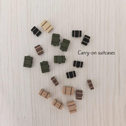 Assorted 3D-printed miniature suitcases in different colors, grouped together to show a mixed set on a light wooden surface.