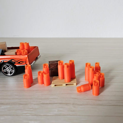 Several miniature orange gas bottles grouped together with a pallet in the background, on a light wood tabletop.