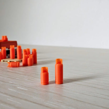Close-up of small and large orange 1:64 scale gas bottles standing side by side on a wooden surface.