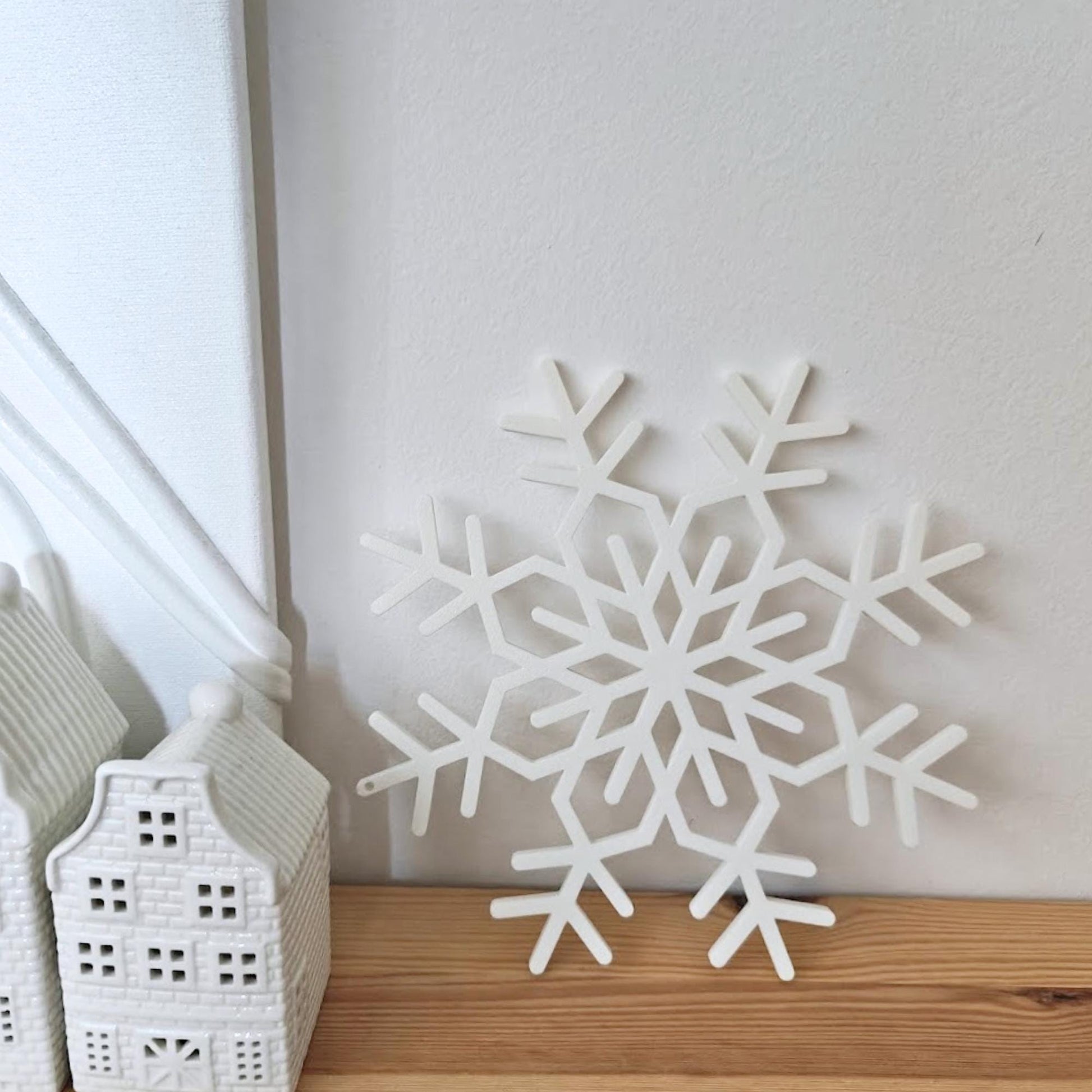 Close-up of a white 3D-printed snowflake ornament placed on a wooden surface.