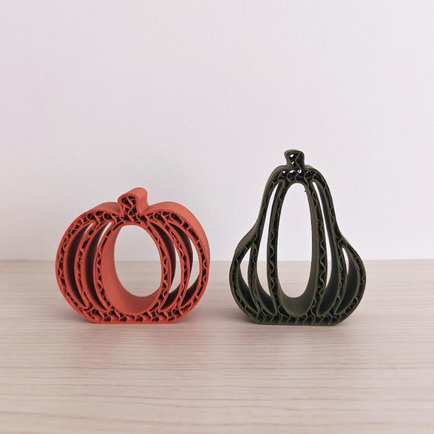 Orange and green 3D-printed pumpkins and gourds displayed together on a neutral background.