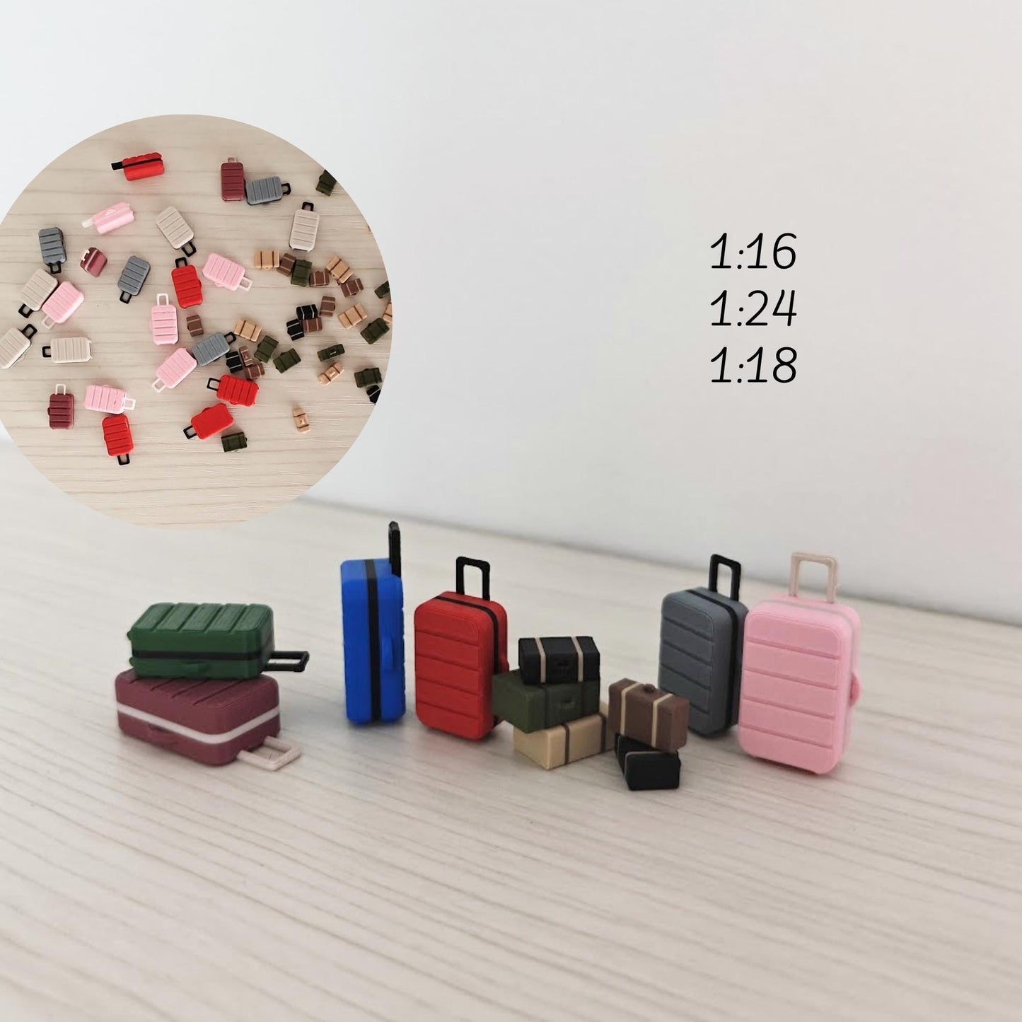 Various 3D-printed miniature suitcases and travel trunks in multiple colors and sizes, arranged in a circle on a light wood surface. Labels indicate scales 1:16, 1:24, and 1:18.