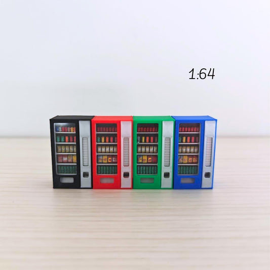 Four 1:64 scale miniature vending machines in blue, green, red, and black arranged in a row on a light wooden background. Each has visible painted snacks and drinks behind clear plastic panels.