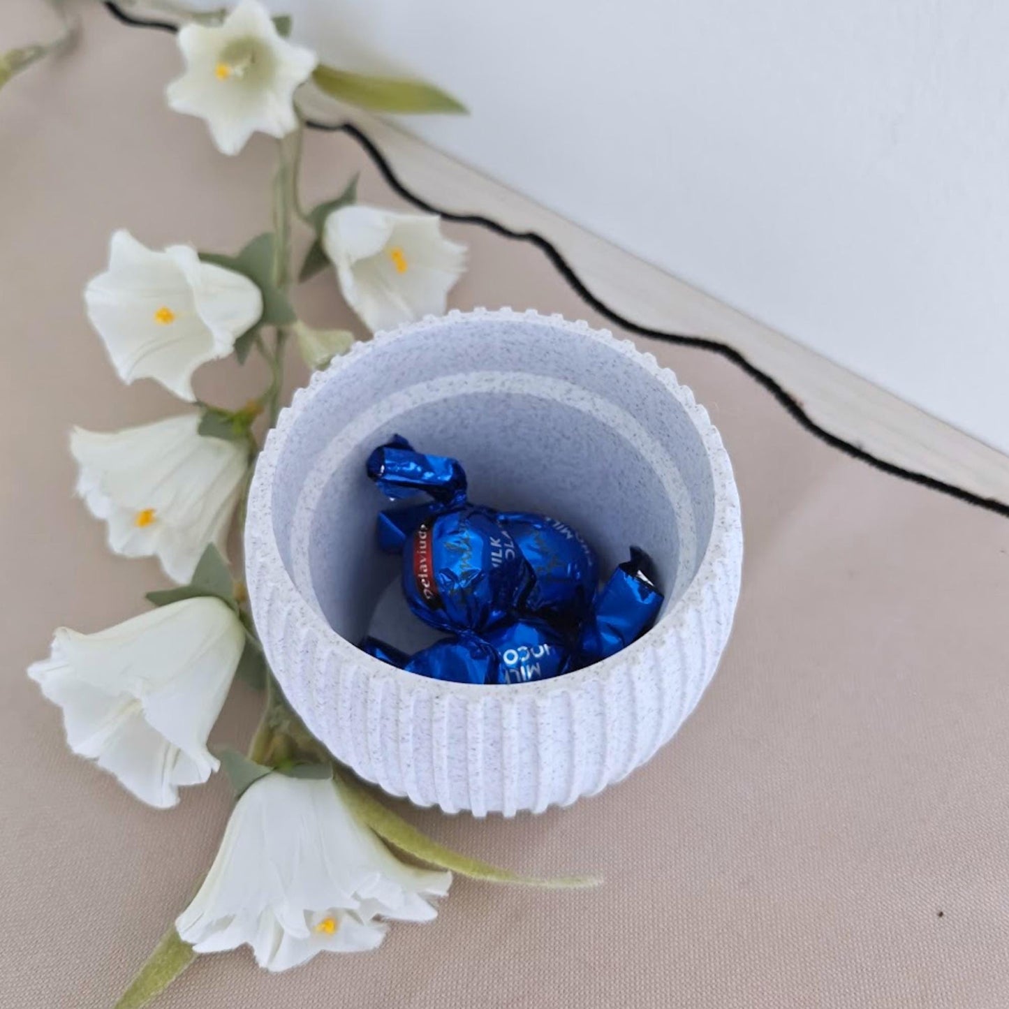 Round ribbed pot used as plant coaster holder with blue candies inside.