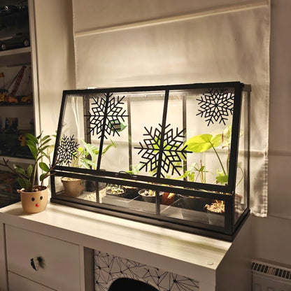 Black Äkerbar greenhouse decorated with black snowflake ornaments and green plants inside.