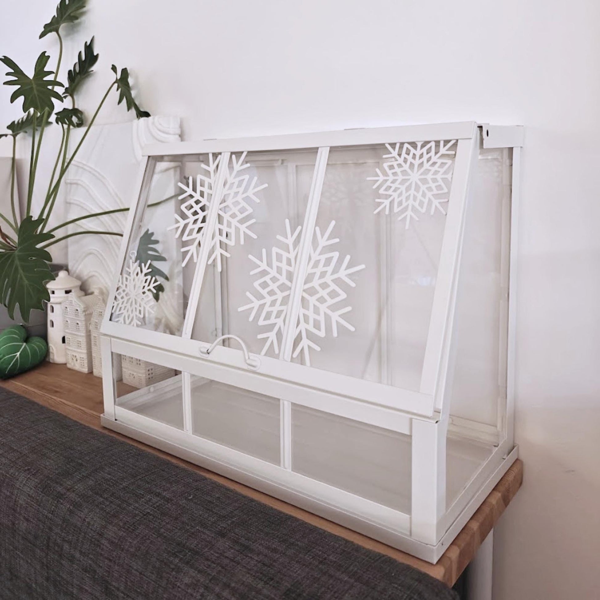 White Äkerbar greenhouse with snowflake decorations shown on wooden shelf.