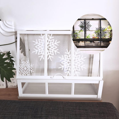 White Äkerbar greenhouse decorated with large white snowflake ornaments on glass panels.