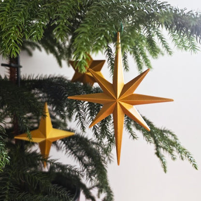 Starburst ornament hanging on Christmas tree branch as festive decor
