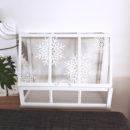 White Äkerbar greenhouse featuring multiple white snowflake decorations in bright room lighting.