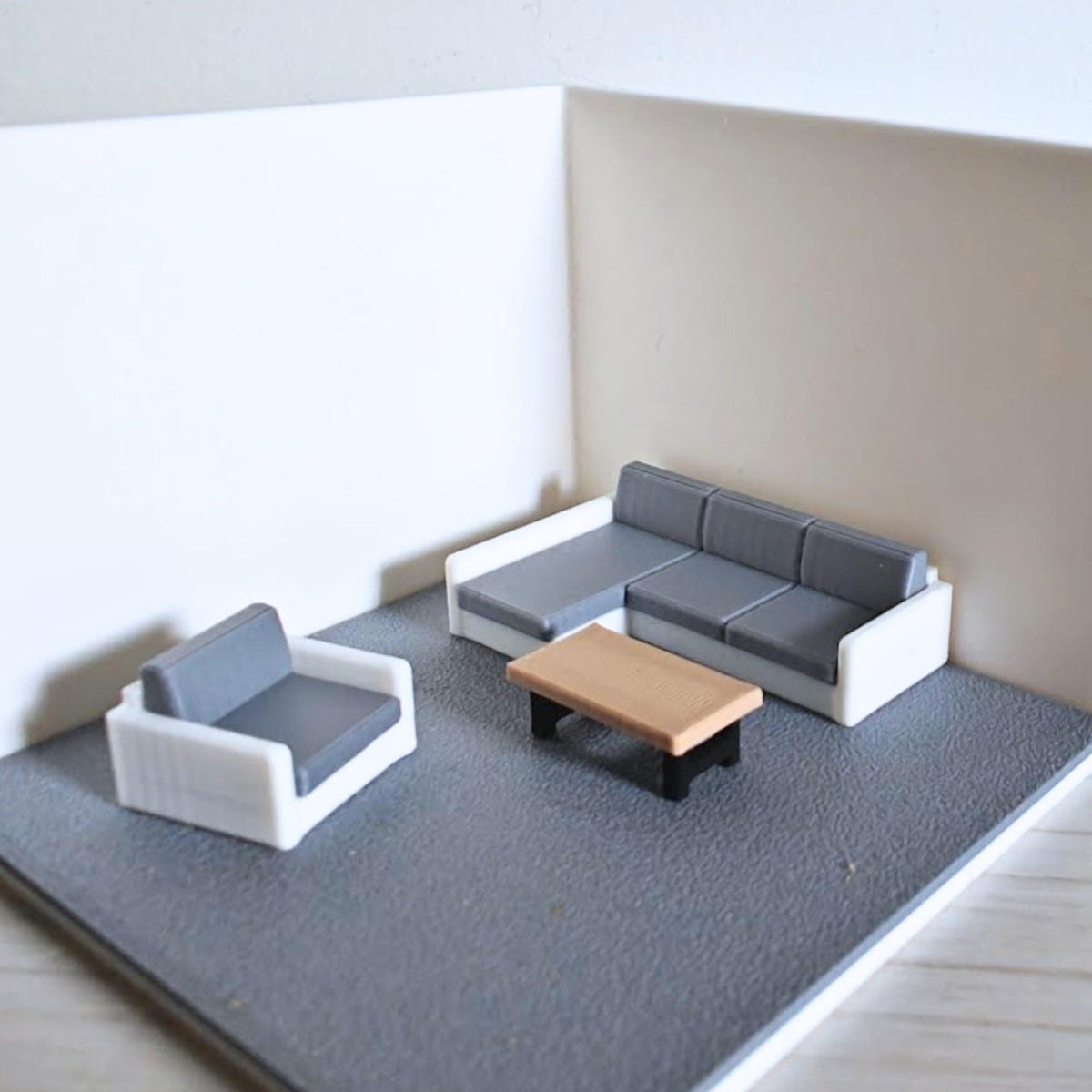 Living room diorama setup with sectional sofa and coffee table in 1:64 scale