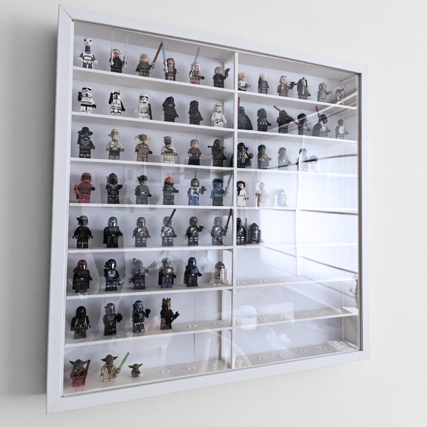 Perspective view of assembled white grid insert inside IKEA Sannahed frame with clear front panel and displayed minifigures.