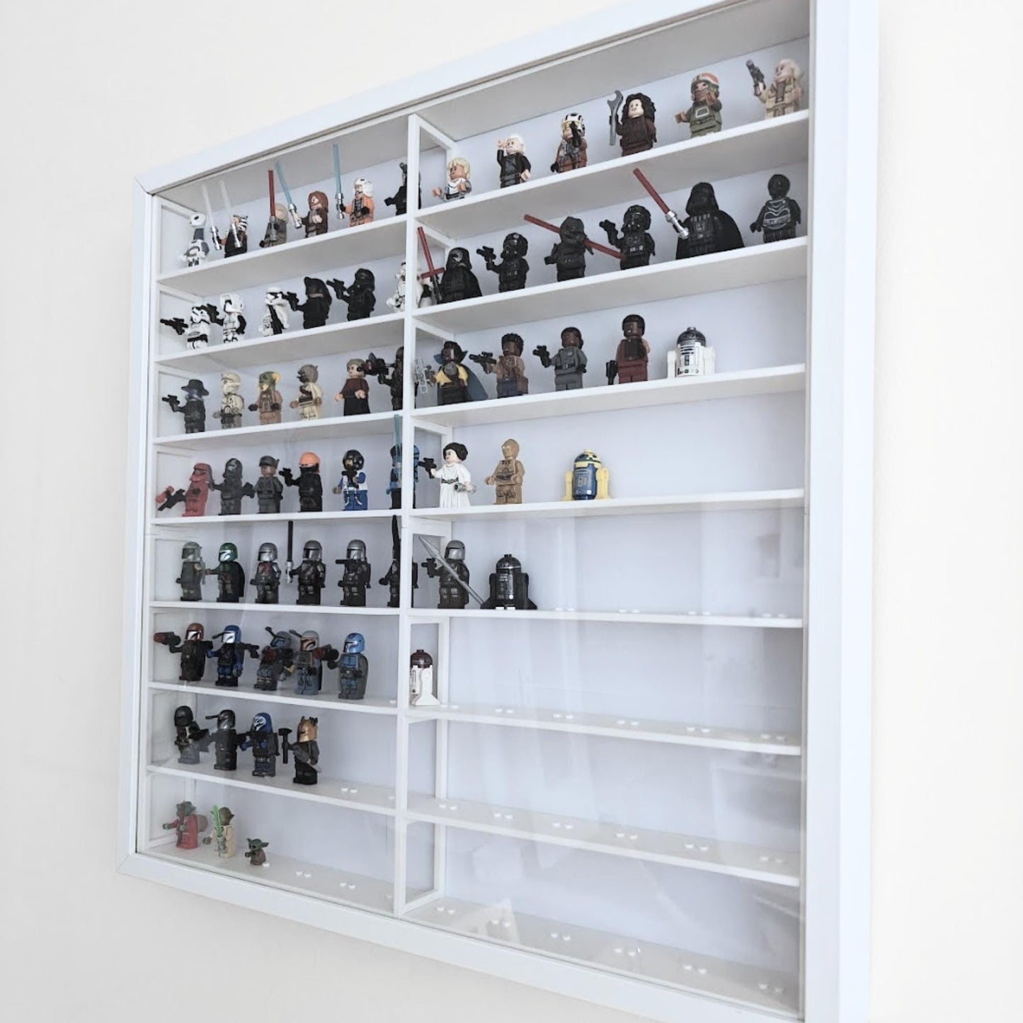 Perspective view of assembled white grid insert inside IKEA Sannahed frame with clear front panel and displayed minifigures.