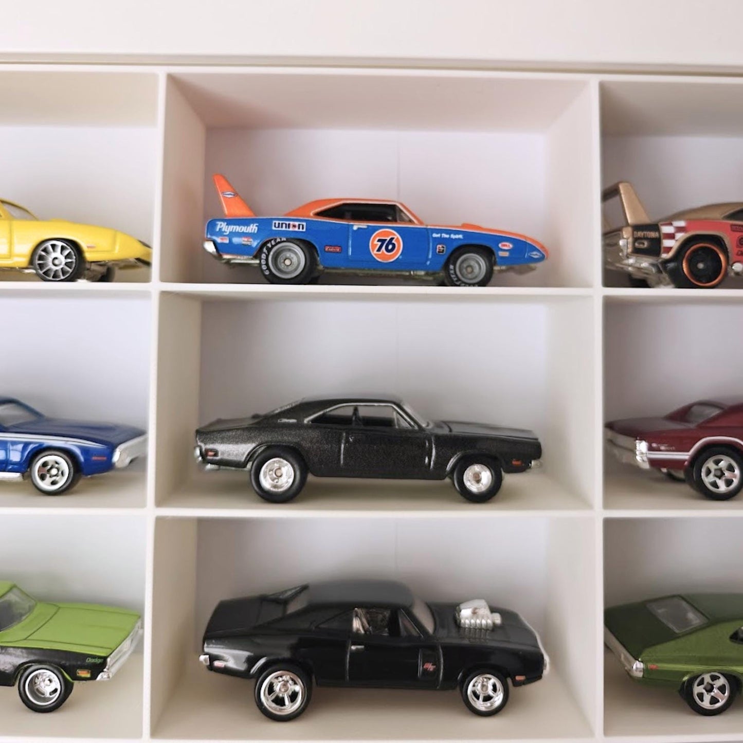 Close-up of Hot Wheels cars arranged in grid compartments