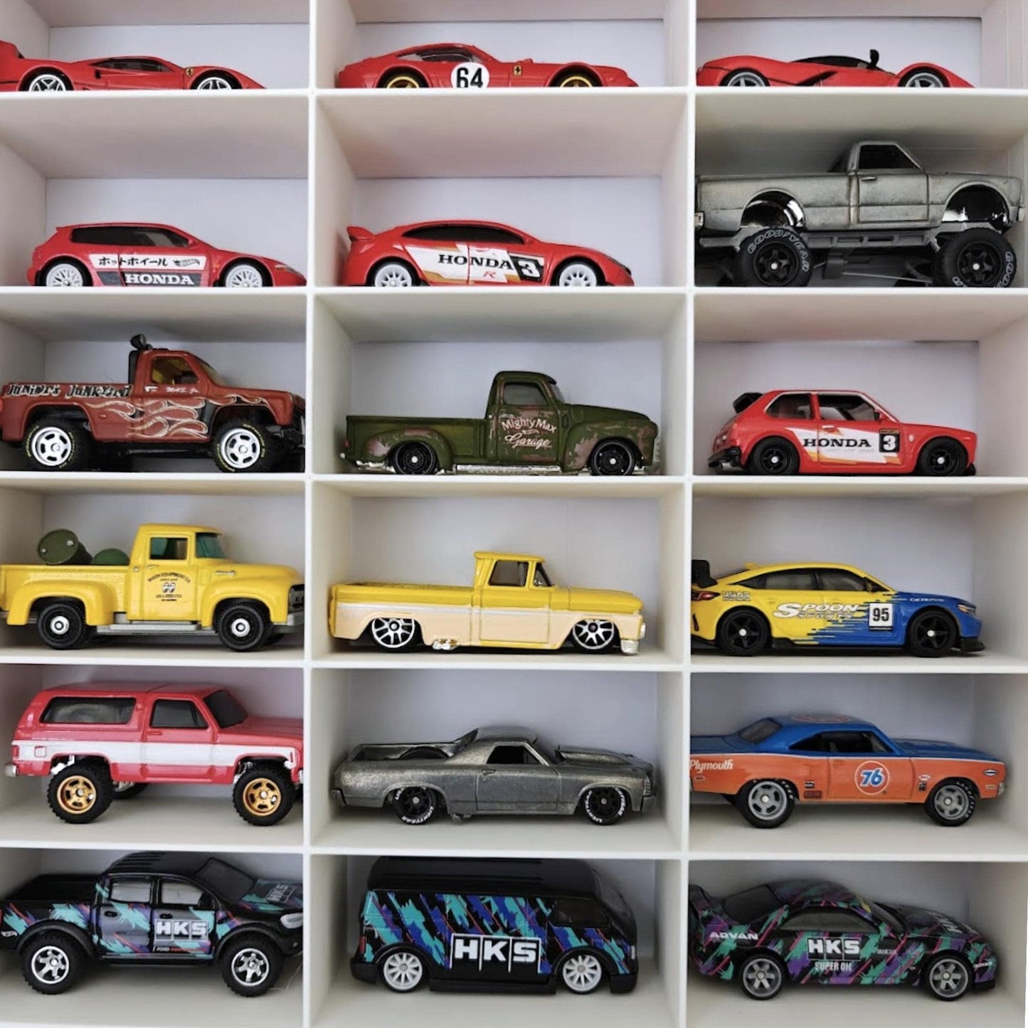Close-up of Hot Wheels cars arranged in display grid compartments