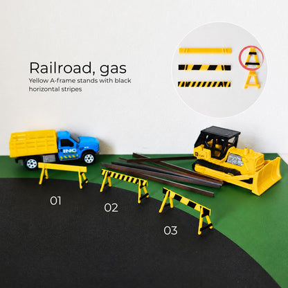 Yellow and black railroad or gas works barricades with construction vehicles and miniature road scene