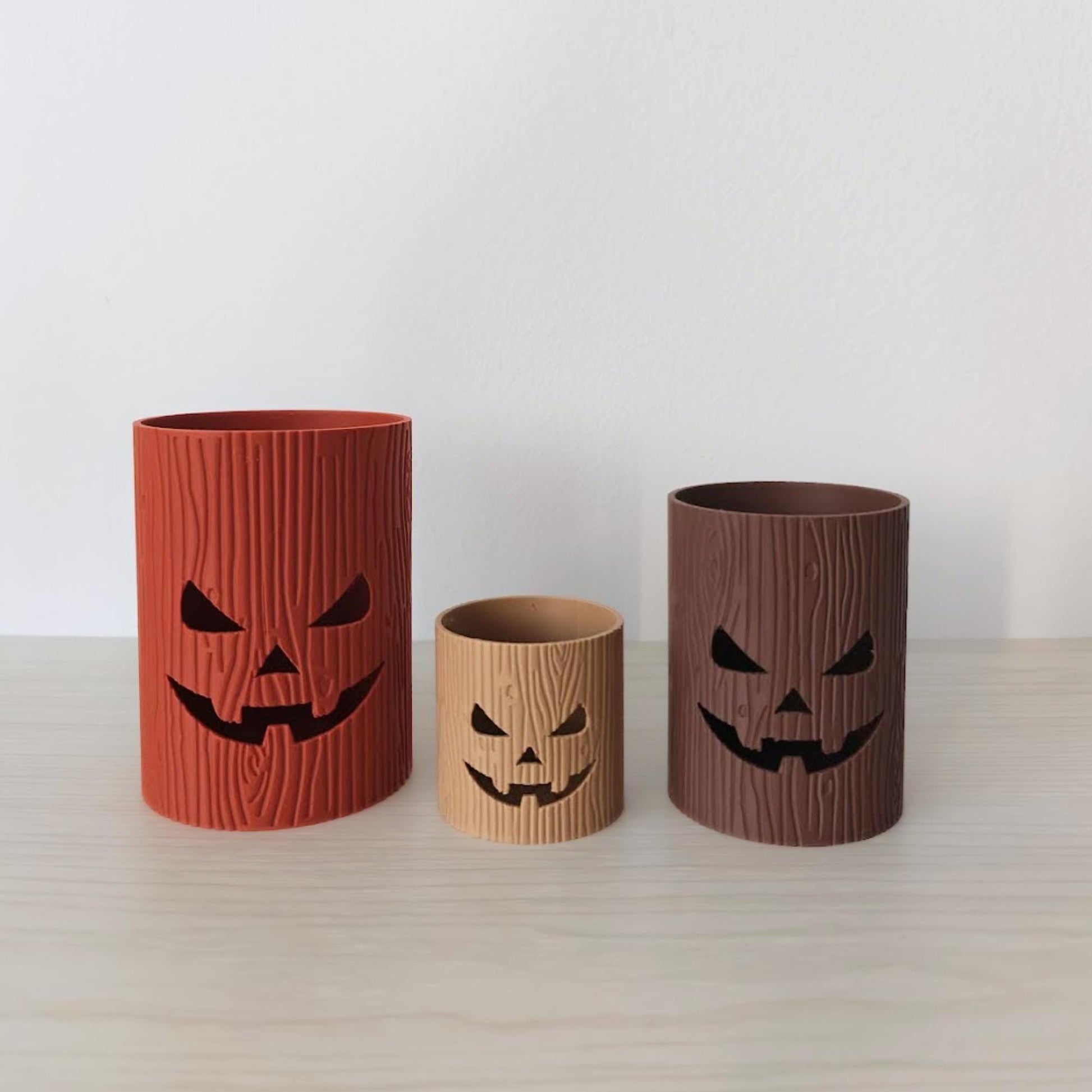 Terracotta, light brown, and dark brown jack-o’-lantern trinket holders with wood grain texture.