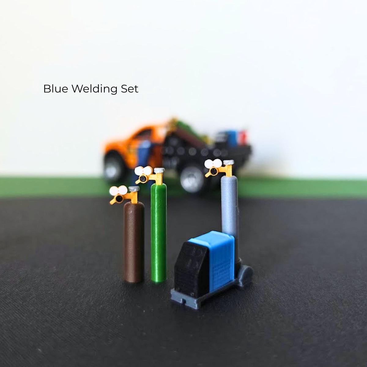 Blue miniature welding set with three gas cylinders, detailed regulators and a wheeled welding machine.