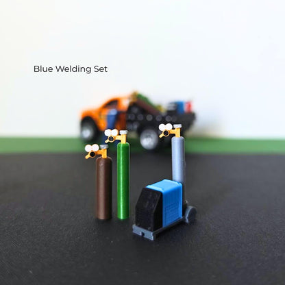Blue miniature welding set with three gas cylinders, detailed regulators and a wheeled welding machine.