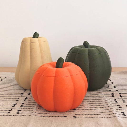 Three pumpkin containers with removable lids in orange, dark green and desert tan, shown together as autumn and Halloween decor.