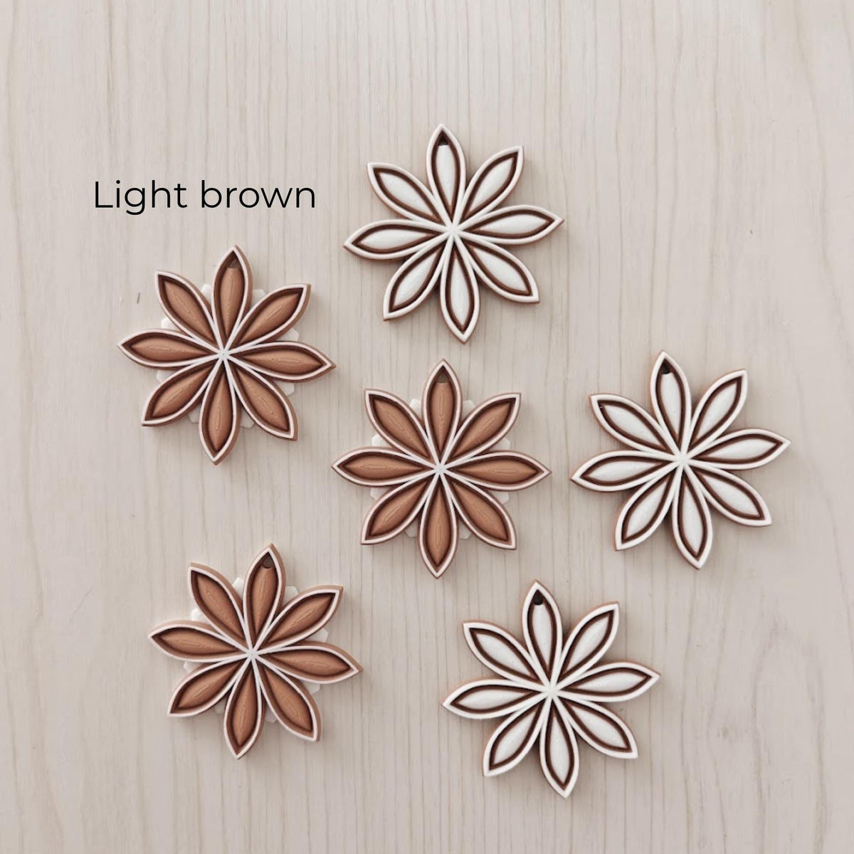 Light brown star anise ornaments in white, tan and brown color combinations.
