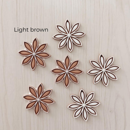 Light brown star anise ornaments in white, tan and brown color combinations.