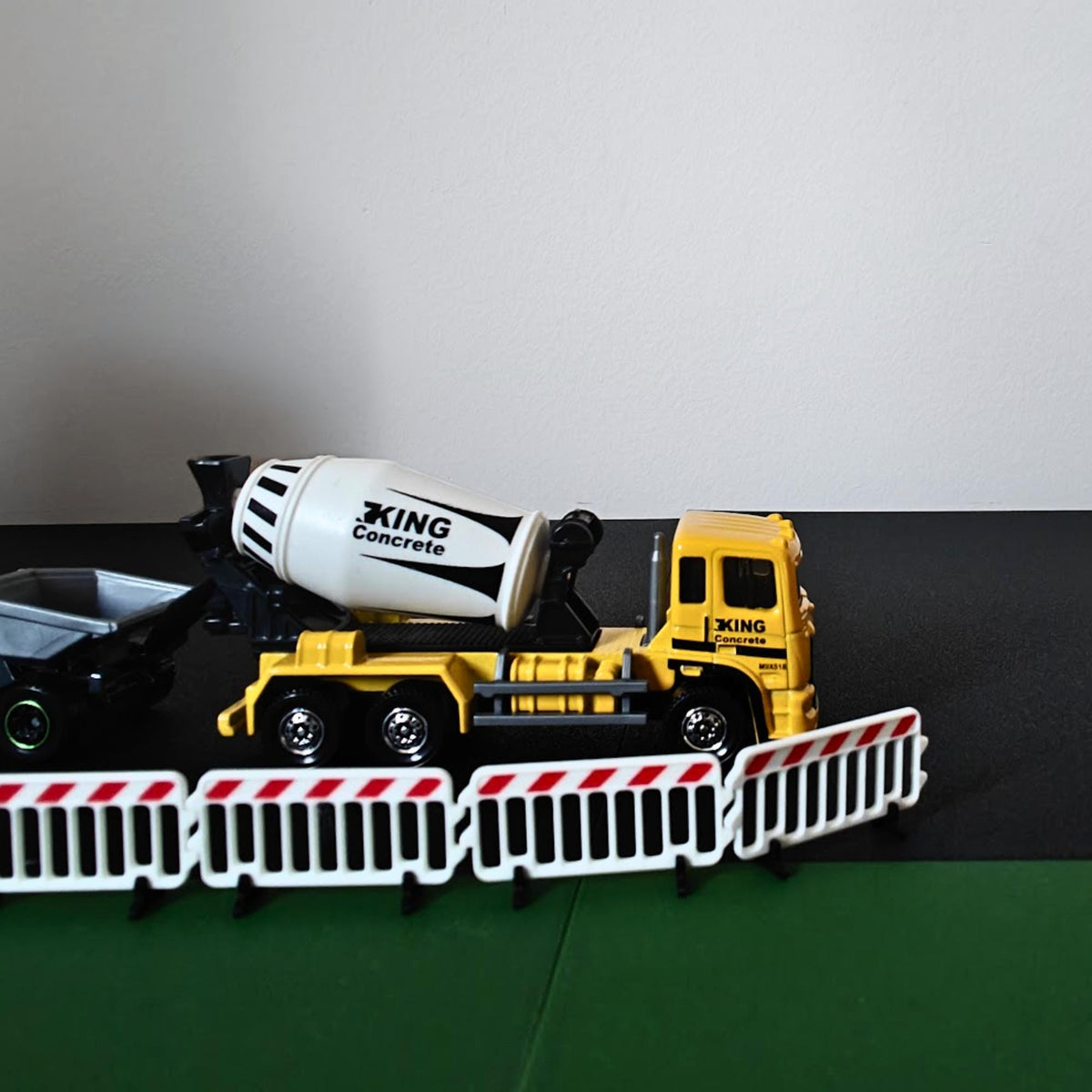 Close-up of miniature road barriers in front of a cement mixer truck