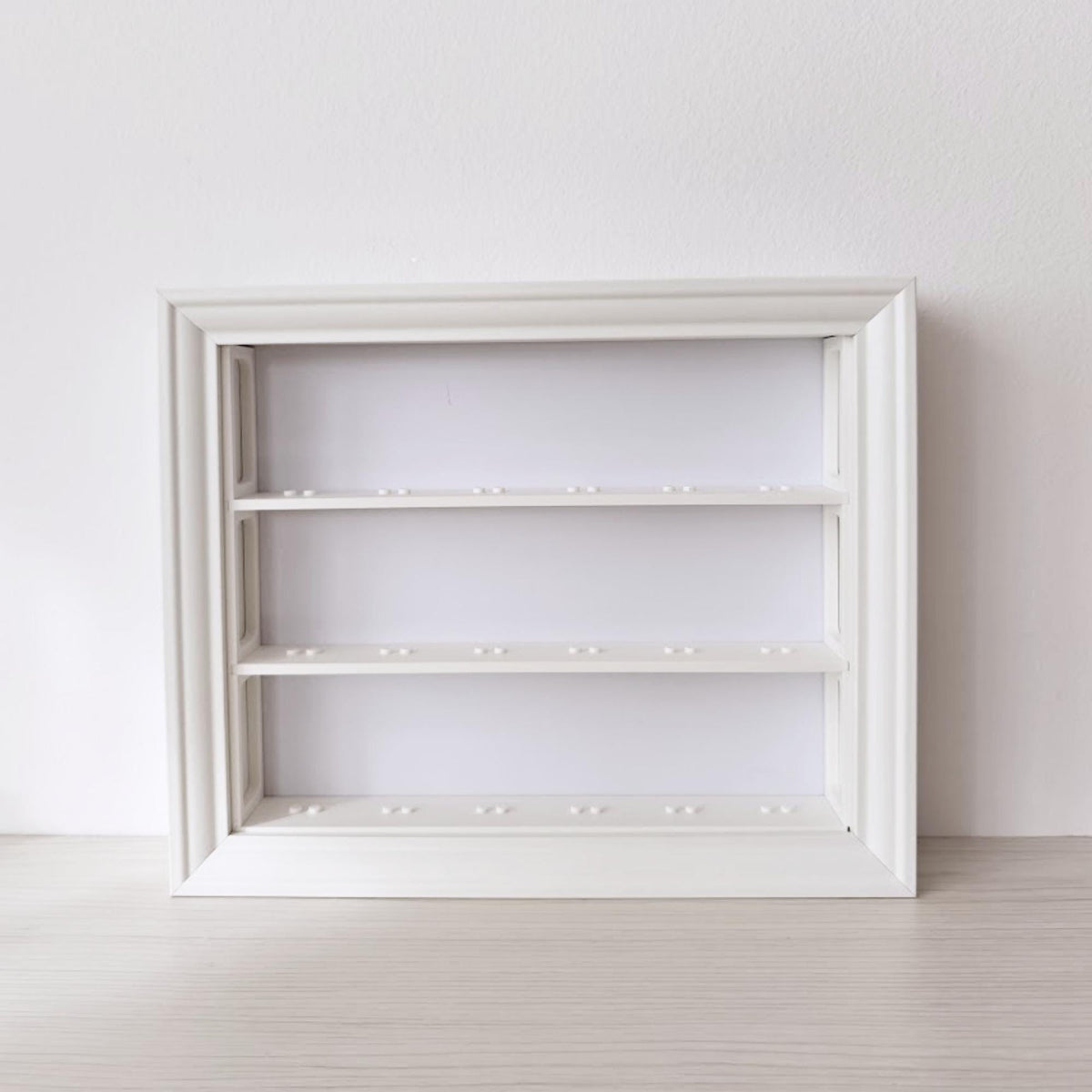 Front view of empty horizontal VÄSTANHED frame insert with three white display shelves.