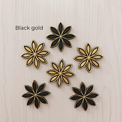 Black and gold star anise ornaments in alternating black and metallic gold designs.