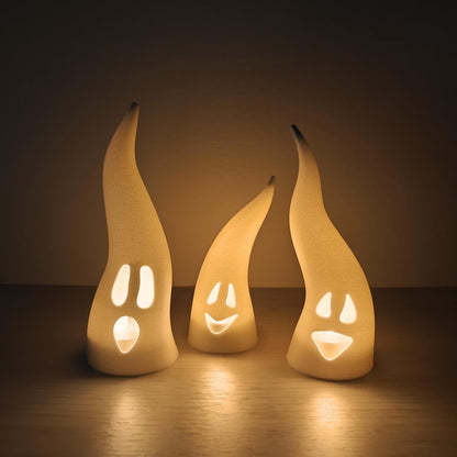 Set of three white ghost LED tealight covers with evil grinning faces illuminated from inside.