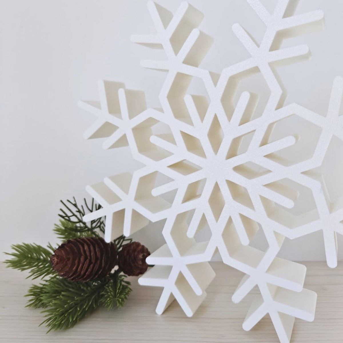 Close-up of large white snowflake Christmas decoration with pinecones and greenery